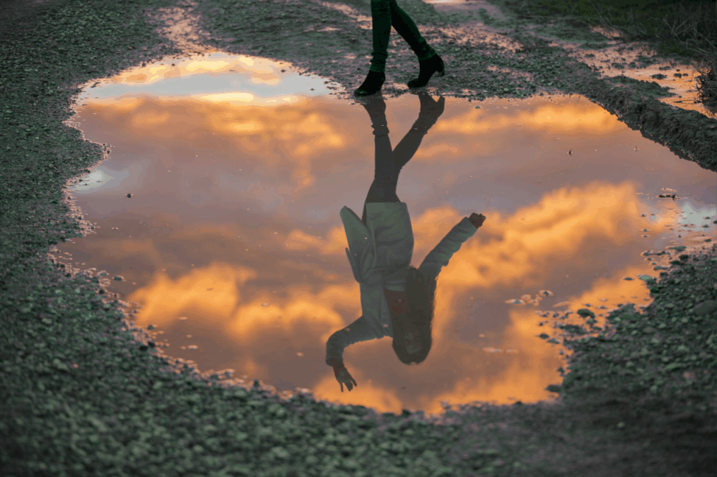 Weerspiegeling van blije vrouw in water - praktijk nicoaching